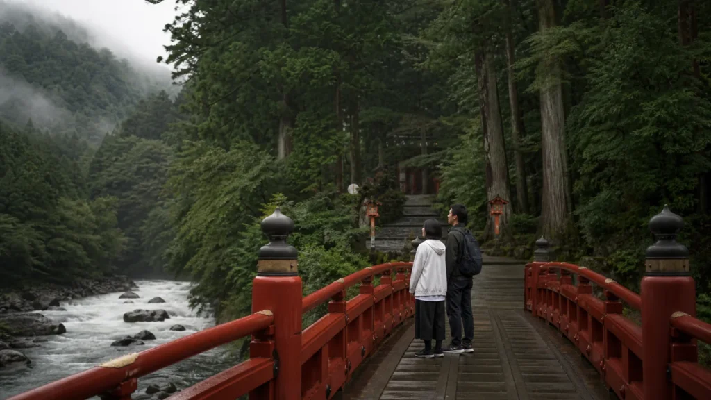 日光山内の入口を思わせる朱塗りの橋と杉山を眺める旅行者