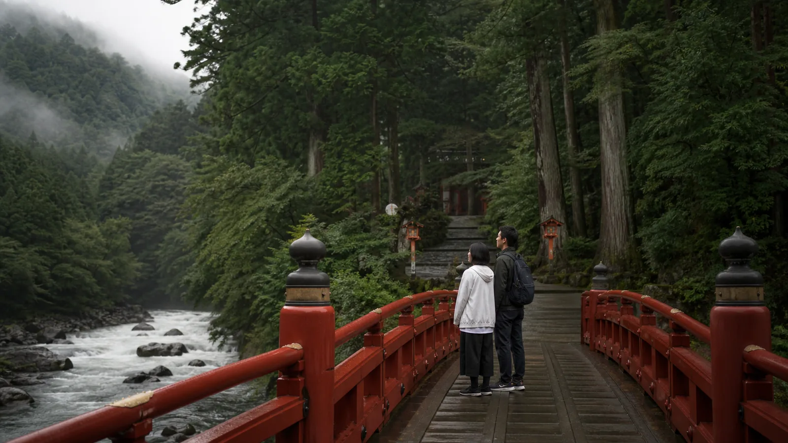 日光山内の入口を思わせる朱塗りの橋と杉山を眺める旅行者