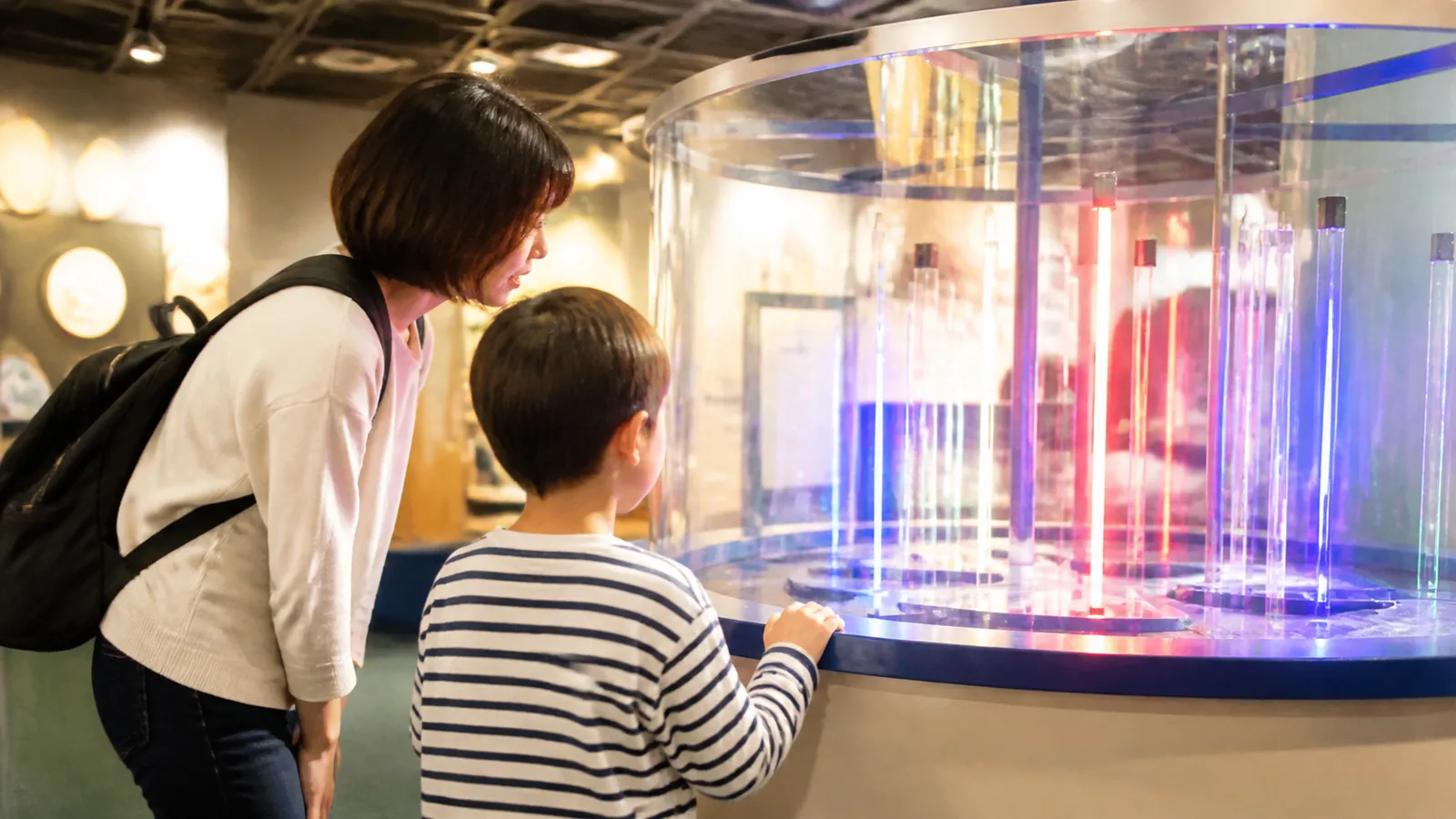 明るい科学展示で体験装置を観察する親子の編集イメージ