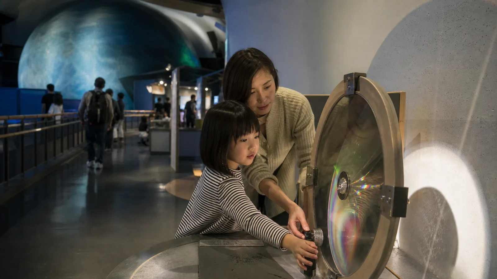 子ども向け科学館を思わせる屋内展示で光の実験を試す親子