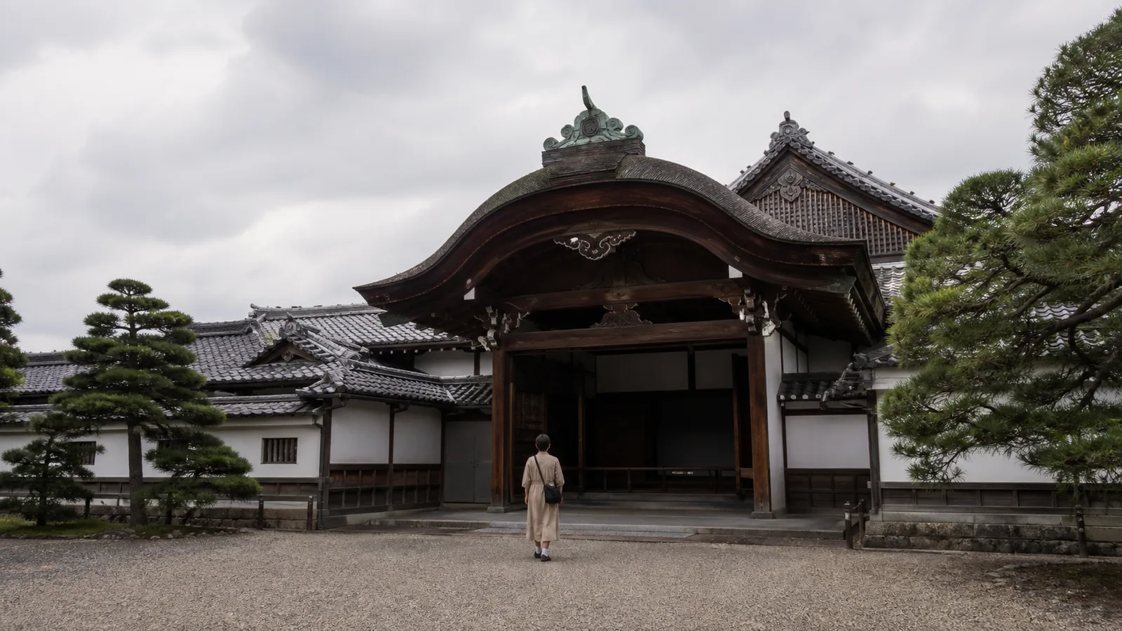 瓦屋根と白壁の本丸御殿風の玄関へ静かに歩く旅行者の編集イメージ