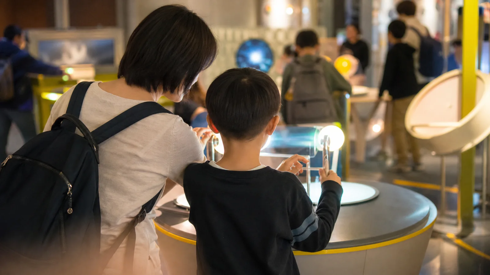 明るい科学館で光の体験展示を試す親子