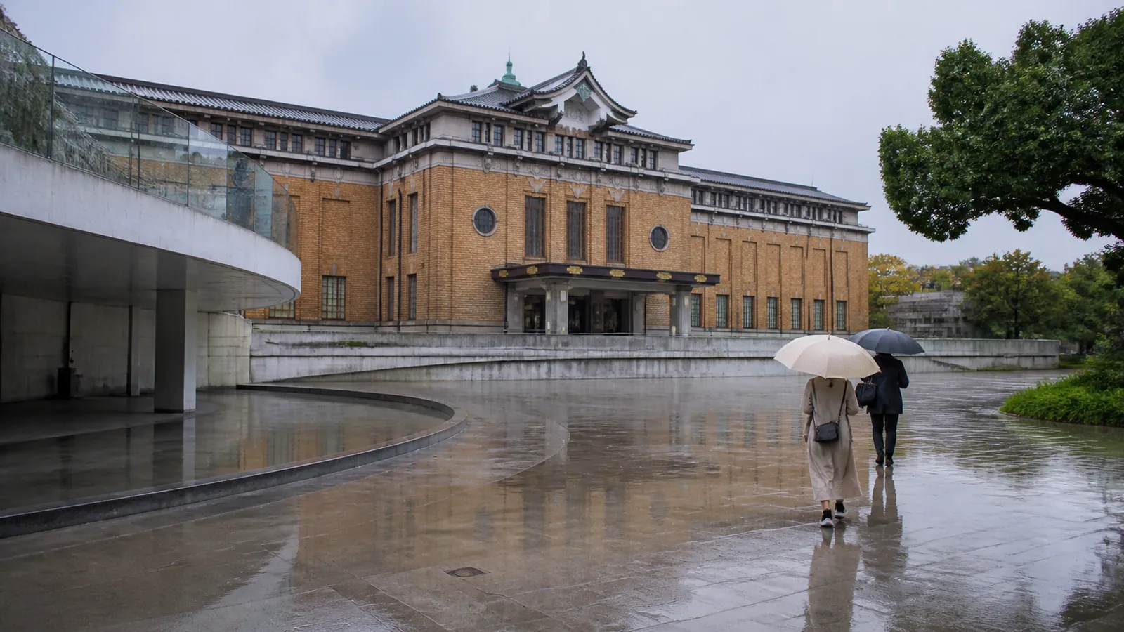 雨の岡崎エリアで近代的な美術館へ向かう旅行者の編集イメージ
