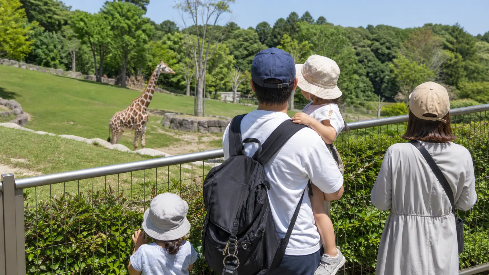 動物園の観覧場所からキリンを見る家族を表した編集イメージ