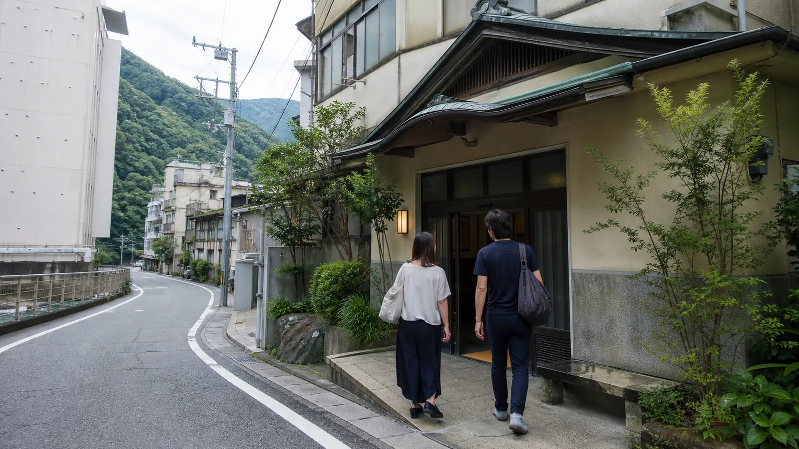 箱根湯本の川沿いにある湯処へ向かう二人の旅行者の編集イメージ