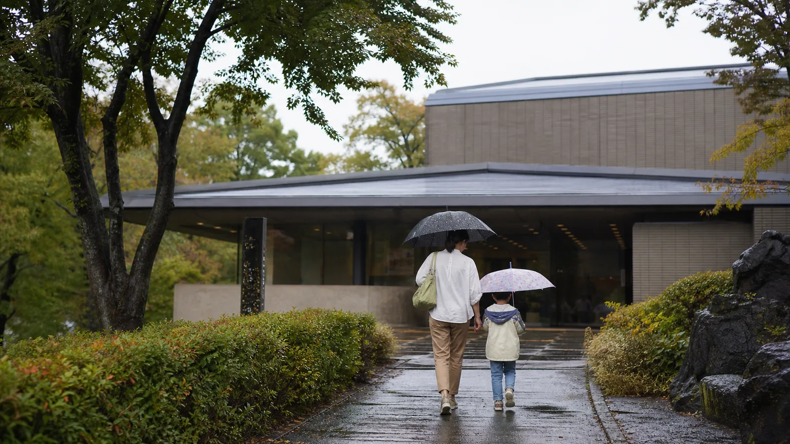 雨の日に盛岡市遺跡の学び館を思わせる文化施設へ入る親子
