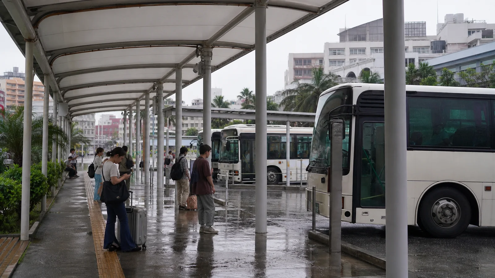 雨の那覇バスターミナルで運行情報を確認する旅行者