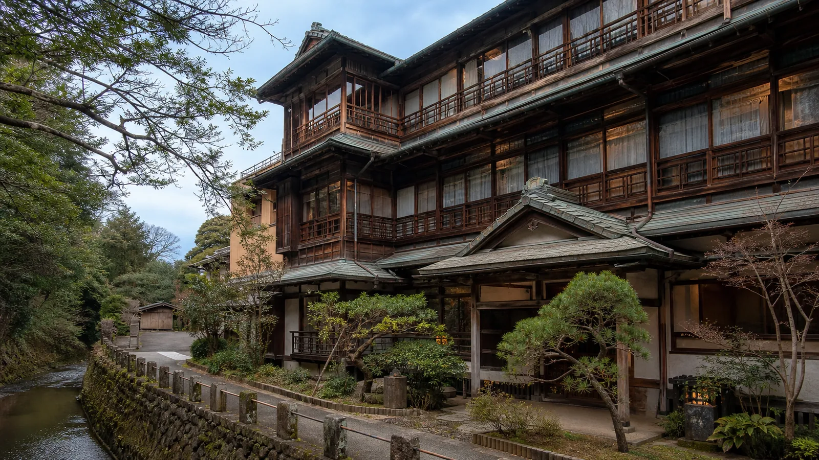 伊東の歴史的な木造旅館建築を川沿いから見た編集イメージ