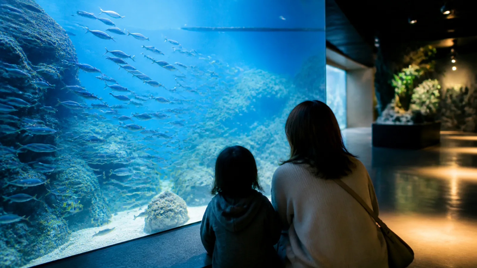 現代的な屋内水族館で青い水槽を観察する親子の編集イメージ