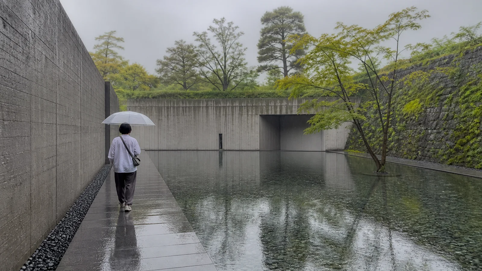 雨の水庭に沿って静かな文化施設を歩く旅行者