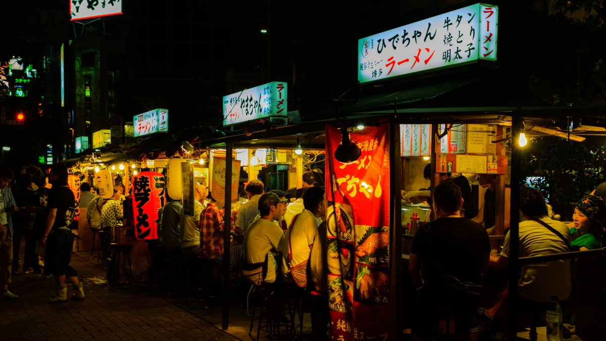 夜の中洲に看板を灯して並ぶ福岡の屋台と利用客