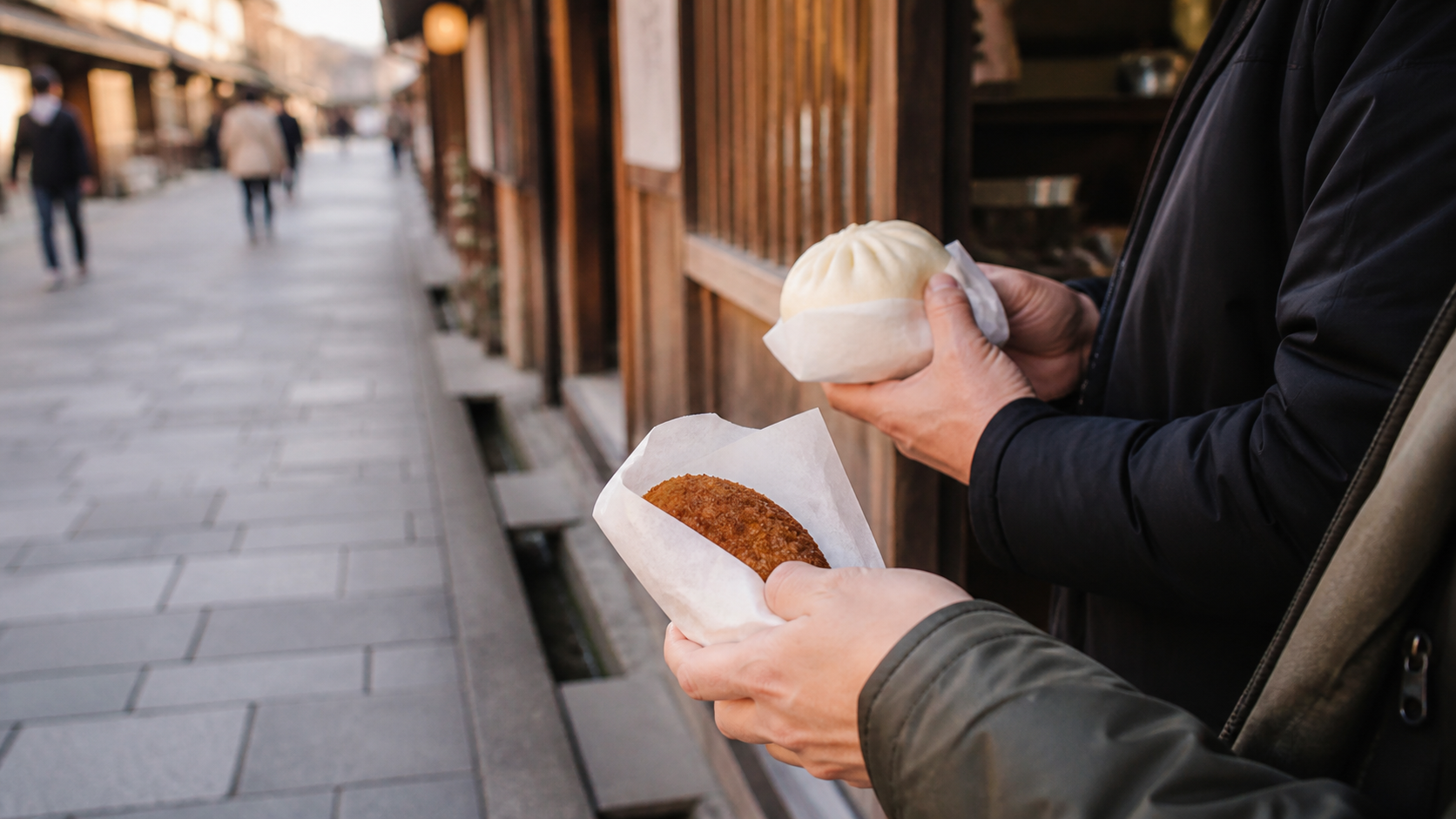 昔ながらの商店街で肉まんとコロッケを手にする旅行者