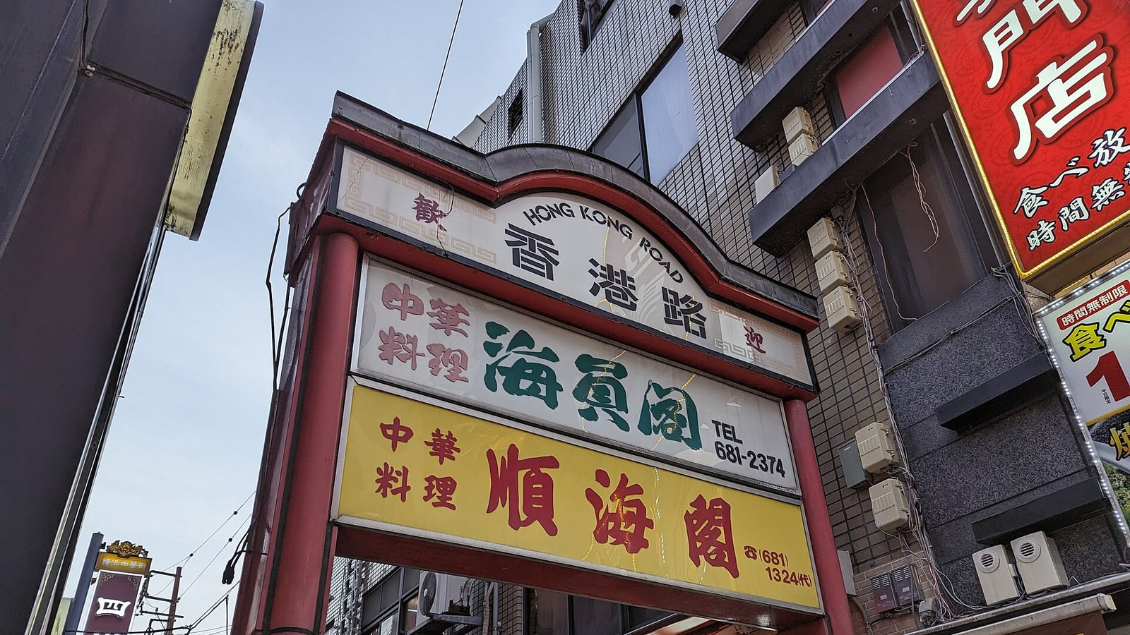 横浜中華街の香港路に立つ赤い門と中華料理店の看板