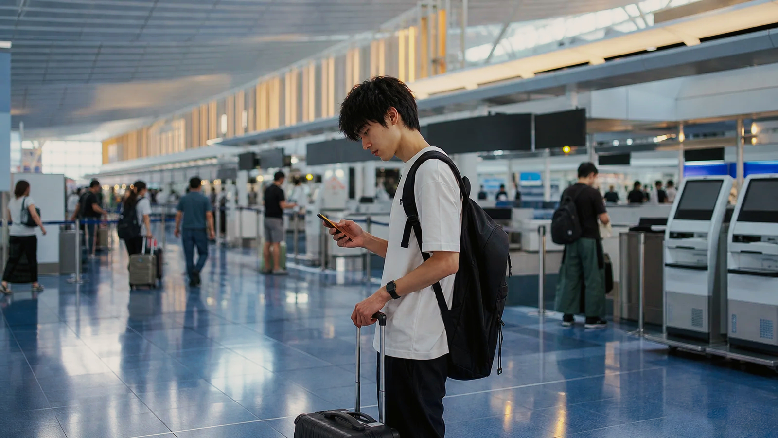 国内線空港の出発ロビーで予約内容を確認する旅行者