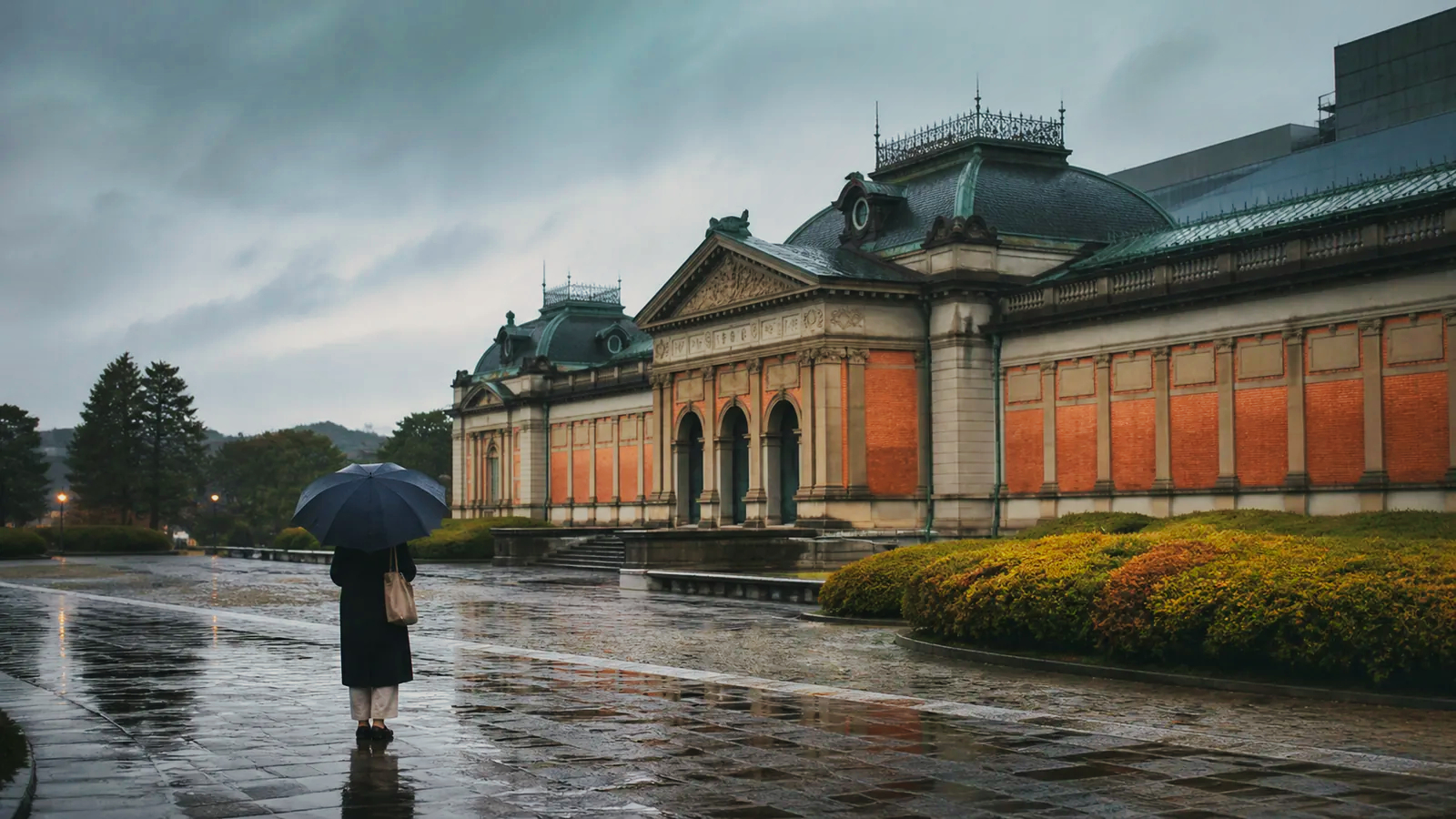 雨に濡れた石畳から京都の歴史的な博物館建築を眺める編集イメージ