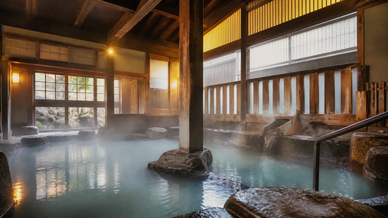 木の梁と石造りの浴槽がある草津温泉の日帰り入浴施設を表した編集イメージ