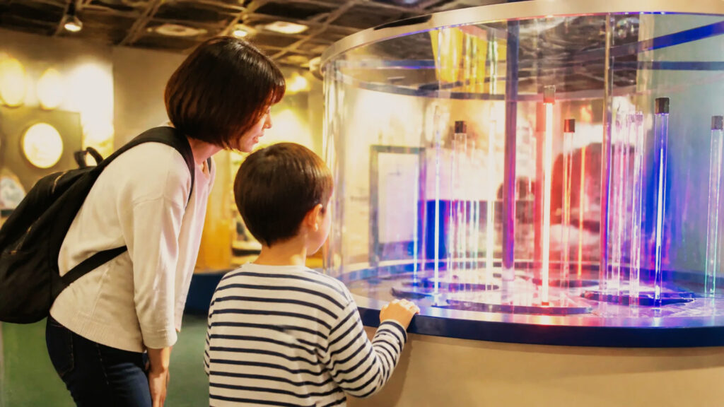 明るい科学展示で体験装置を観察する親子の編集イメージ