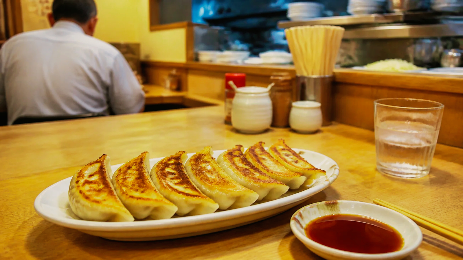 宇都宮の気取らない餃子店で焼き餃子を味わう旅行者