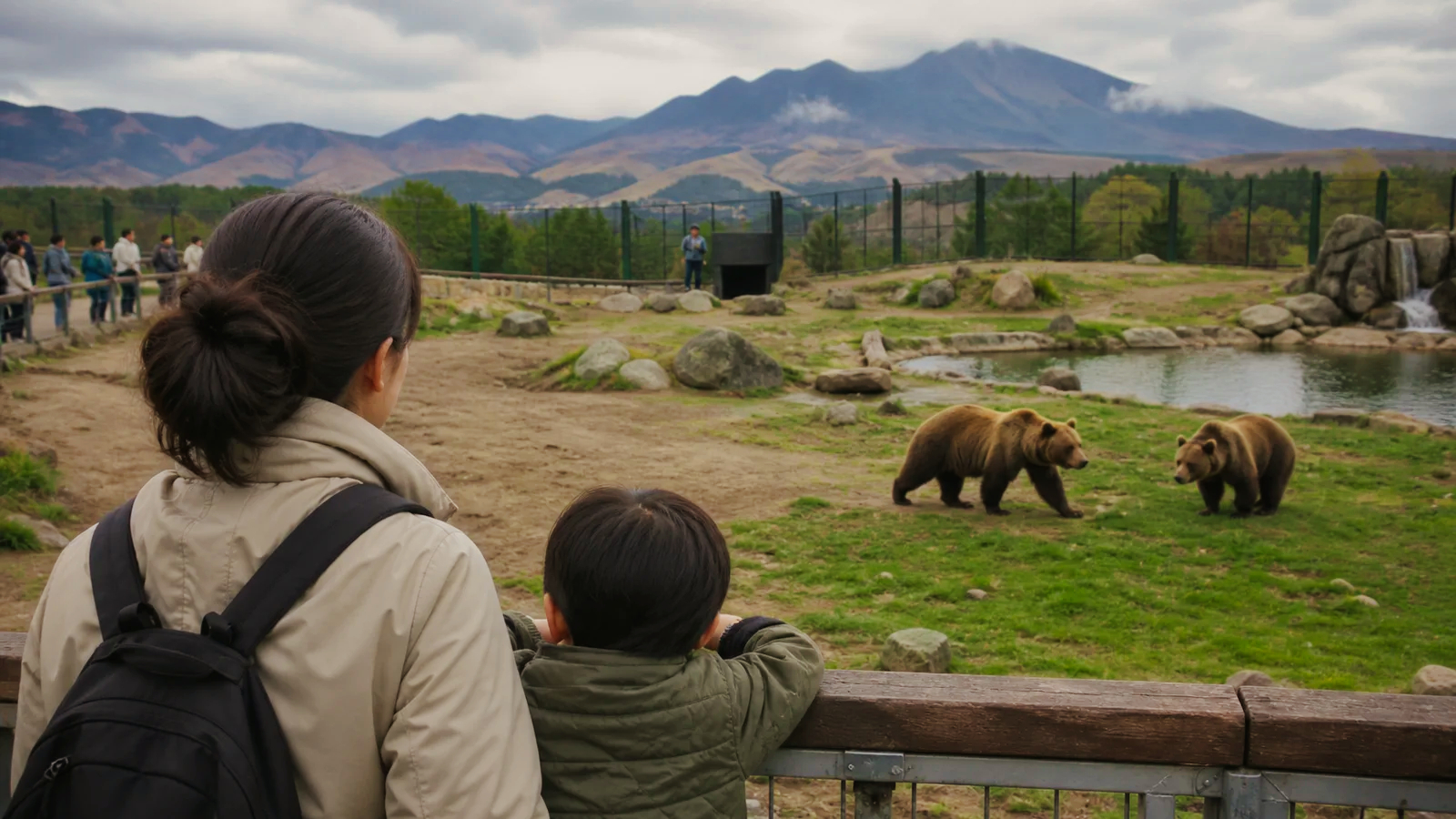 阿蘇を思わせる山並みの前でクマを観察する親子
