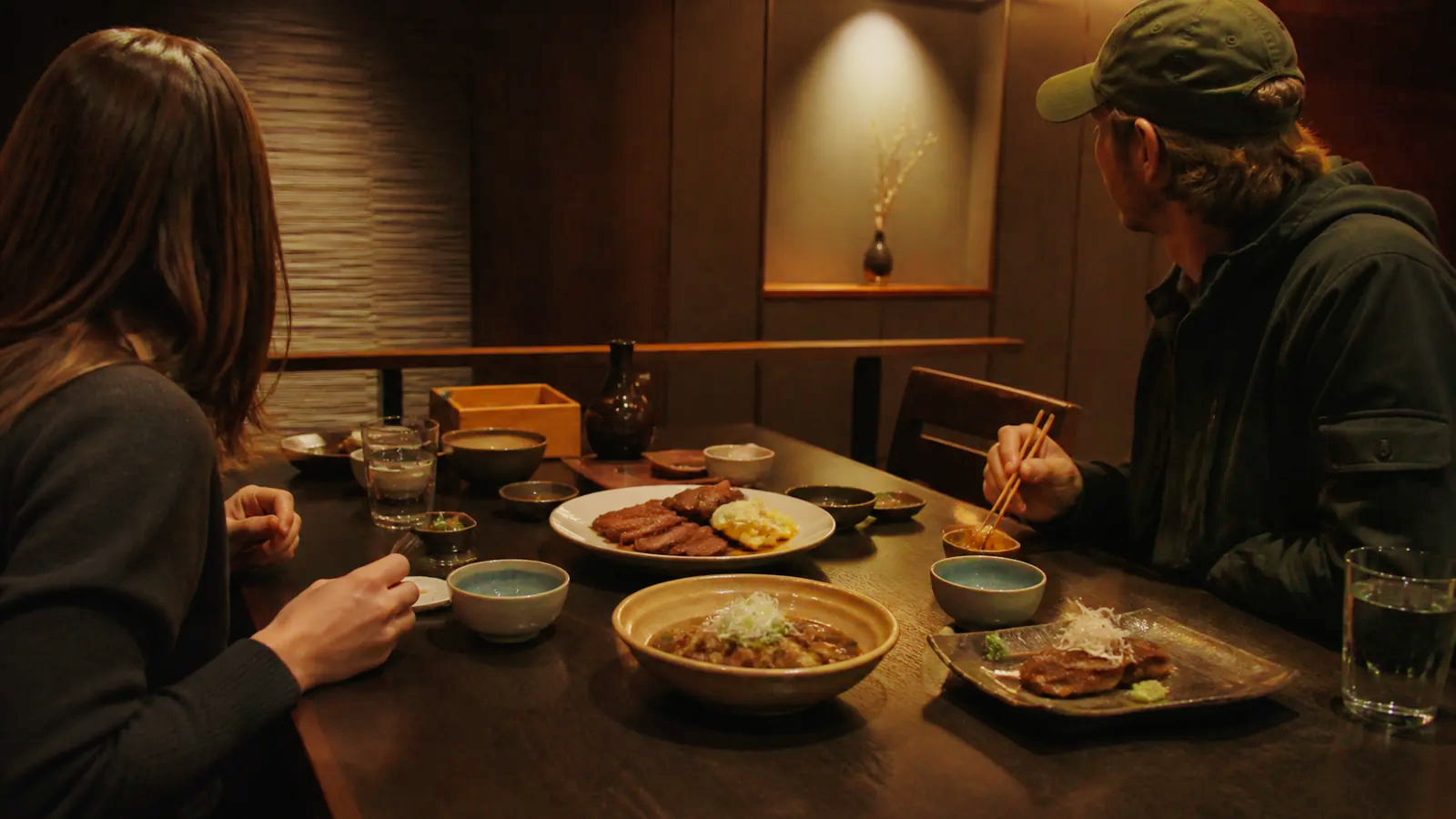落ち着いた食事処で複数の牛たん料理を囲む二人の編集イメージ