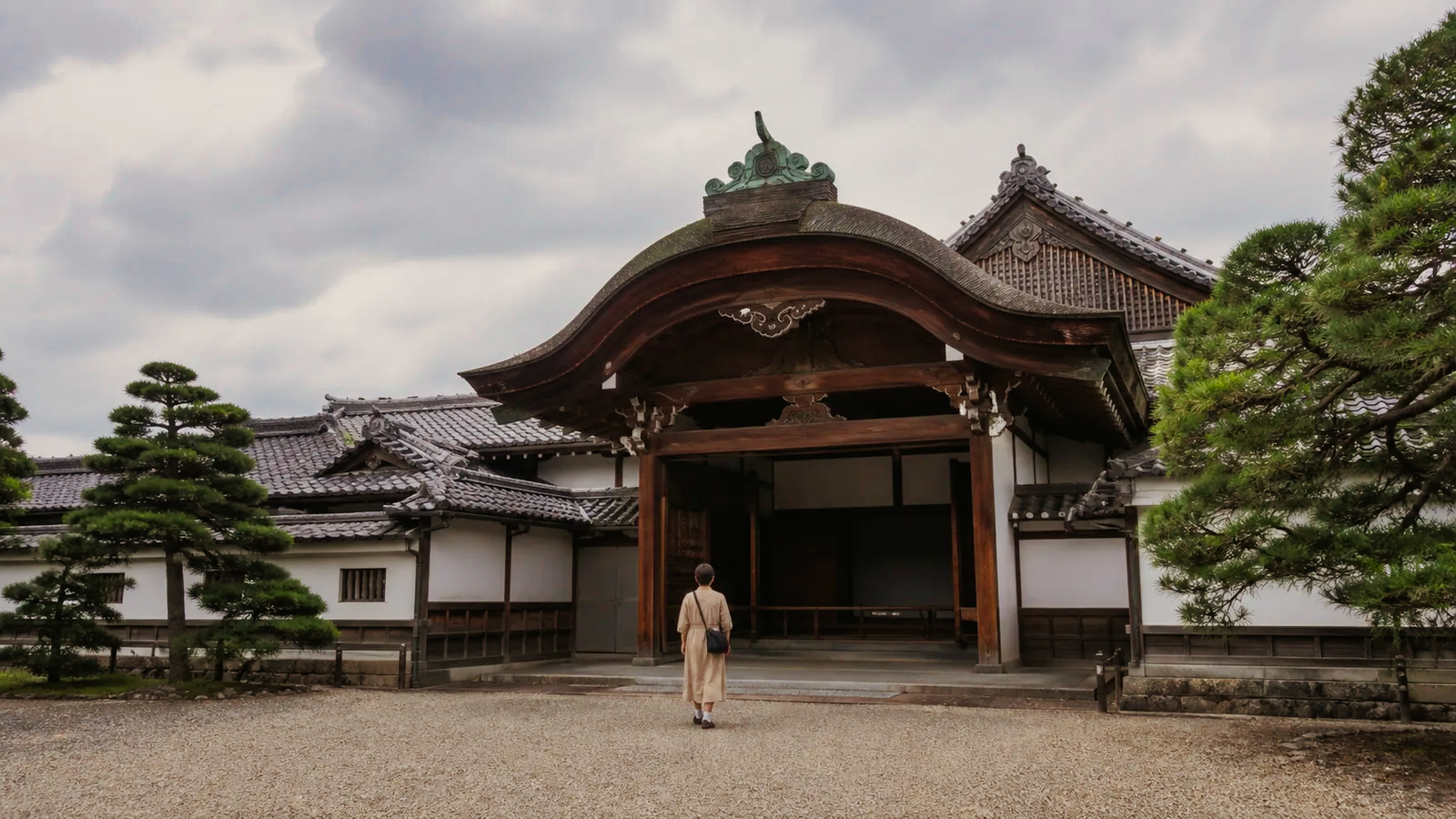 瓦屋根と白壁の本丸御殿風の玄関へ静かに歩く旅行者の編集イメージ