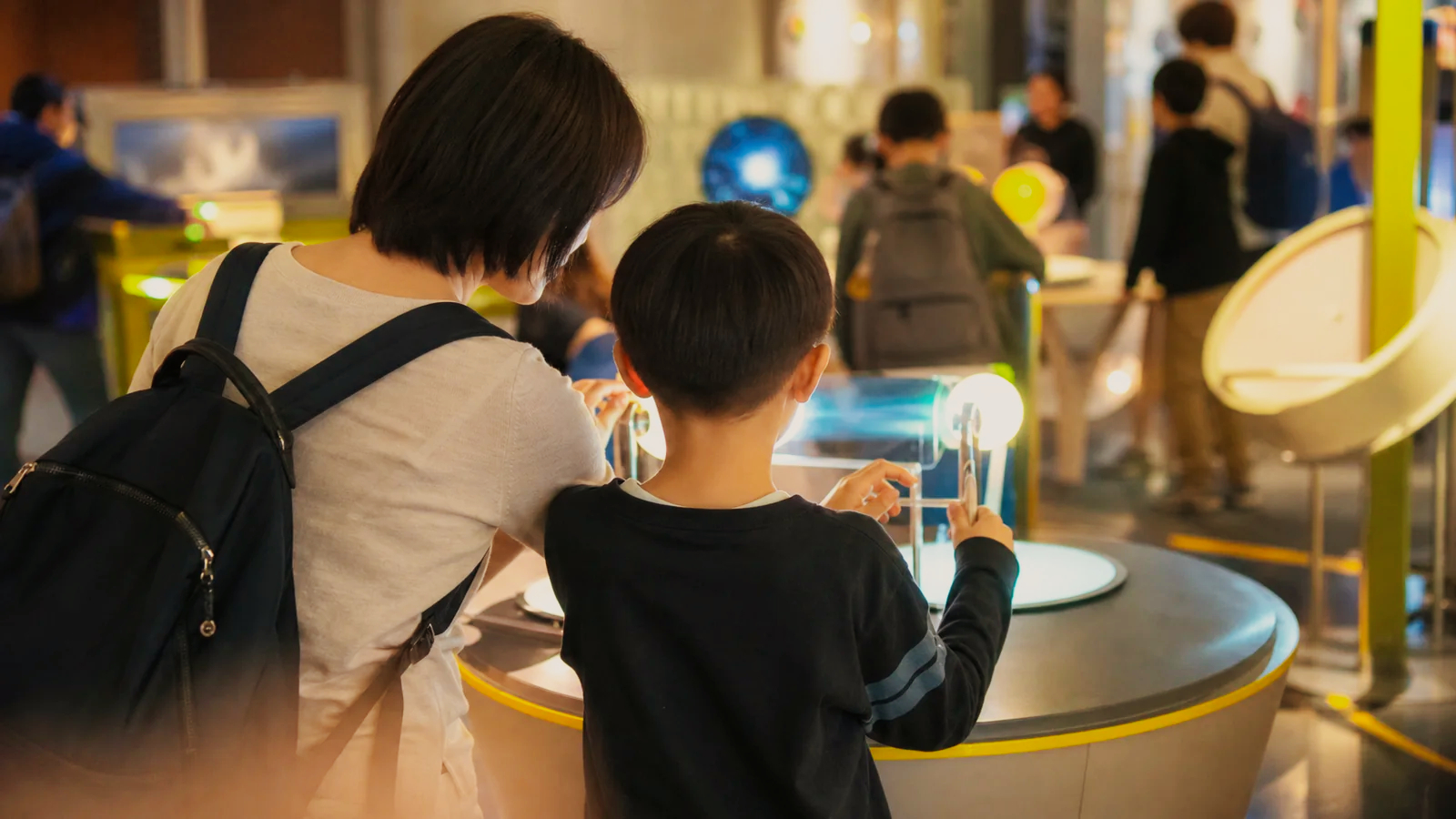 明るい科学館で光の体験展示を試す親子
