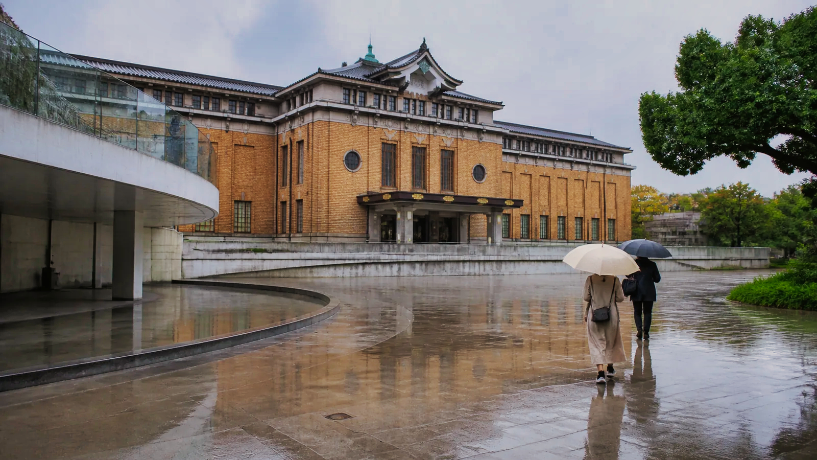 雨の岡崎エリアで近代的な美術館へ向かう旅行者の編集イメージ