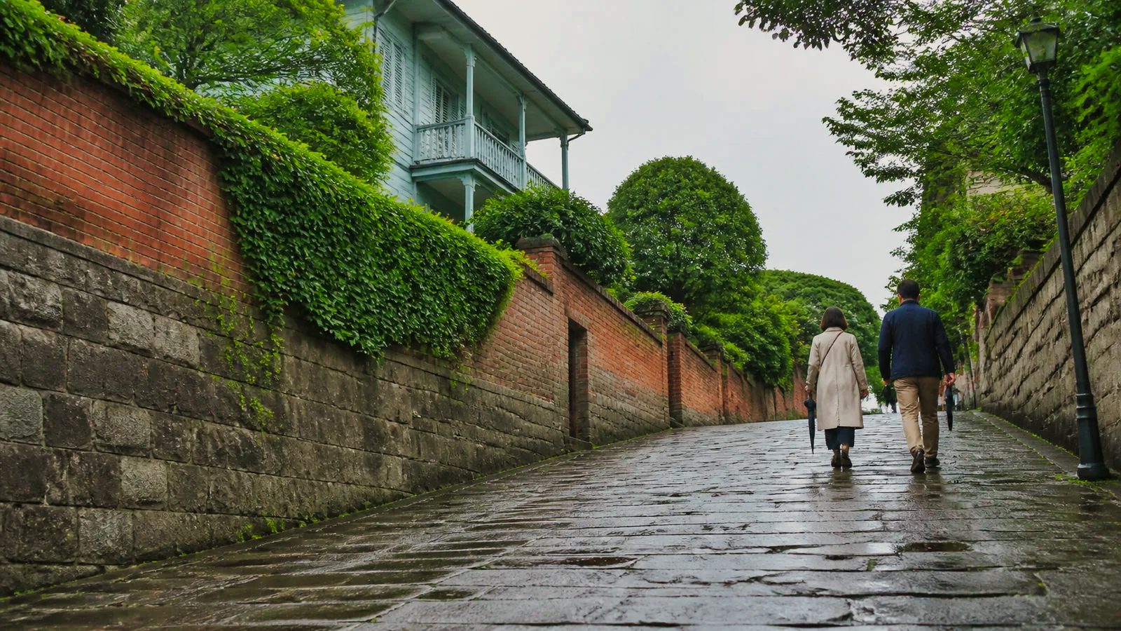 雨上がりの石畳の坂を歩く旅行者の編集イメージ