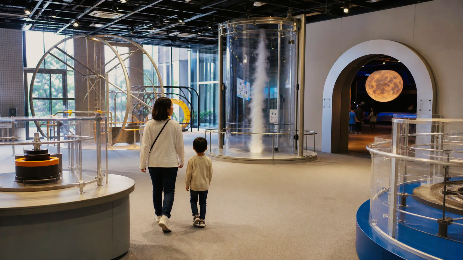親子が大型の科学実験展示と宇宙展示を見学する編集イメージ