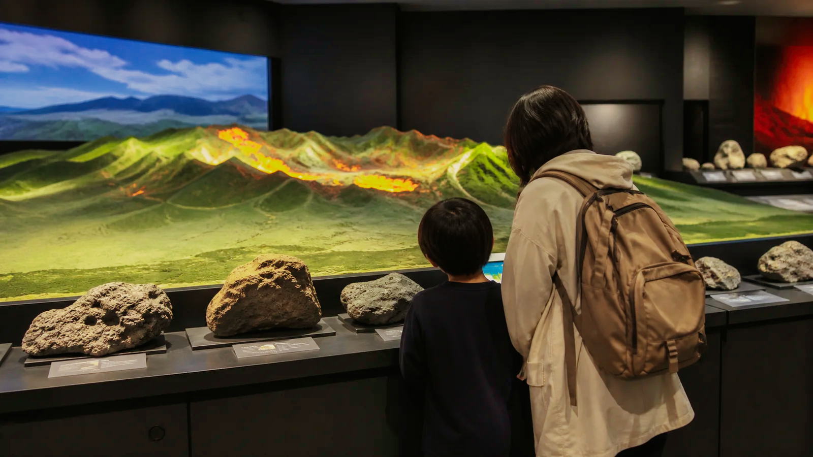 火山の地形模型と岩石展示を見る親子
