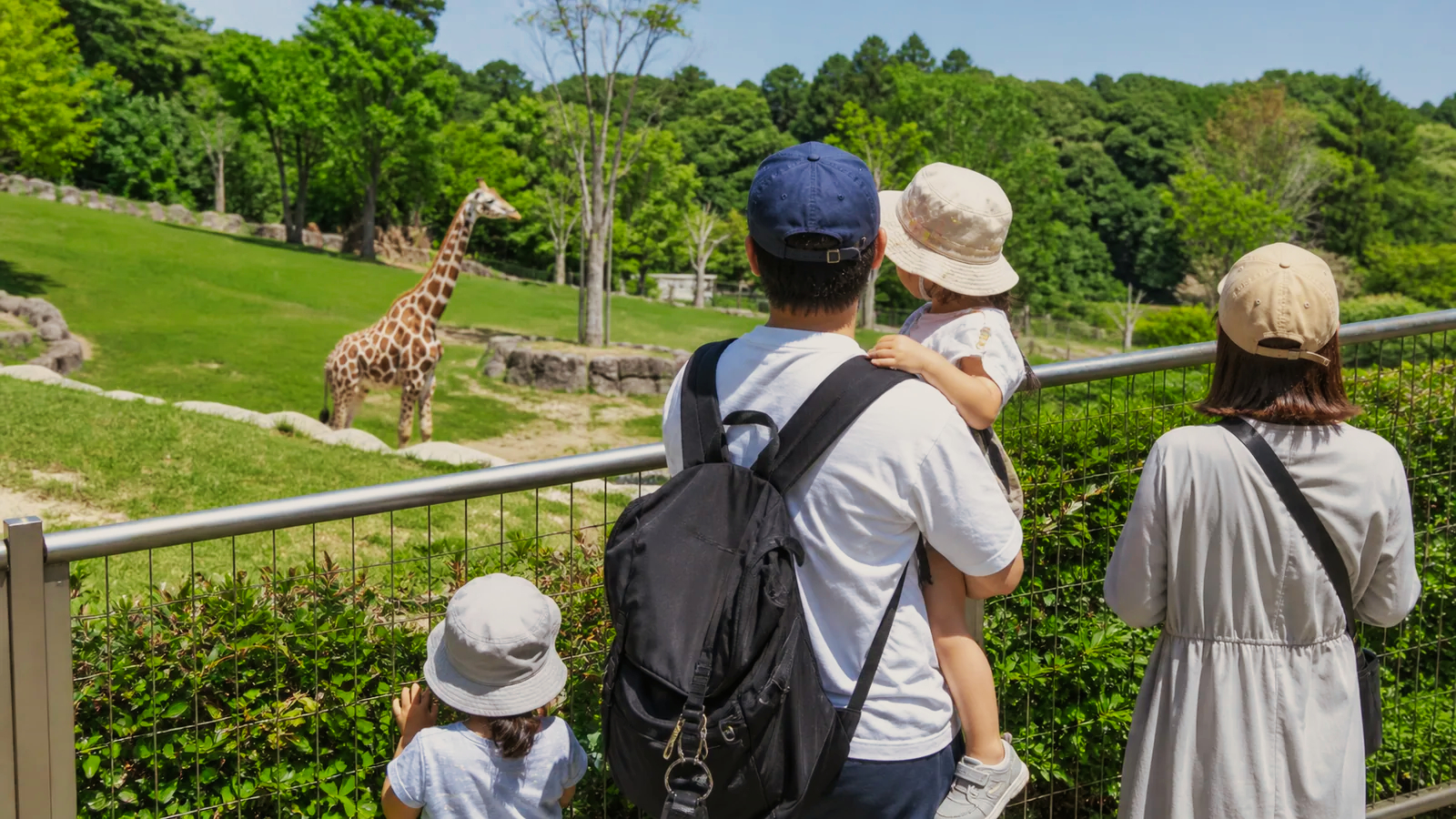 動物園の観覧場所からキリンを見る家族を表した編集イメージ