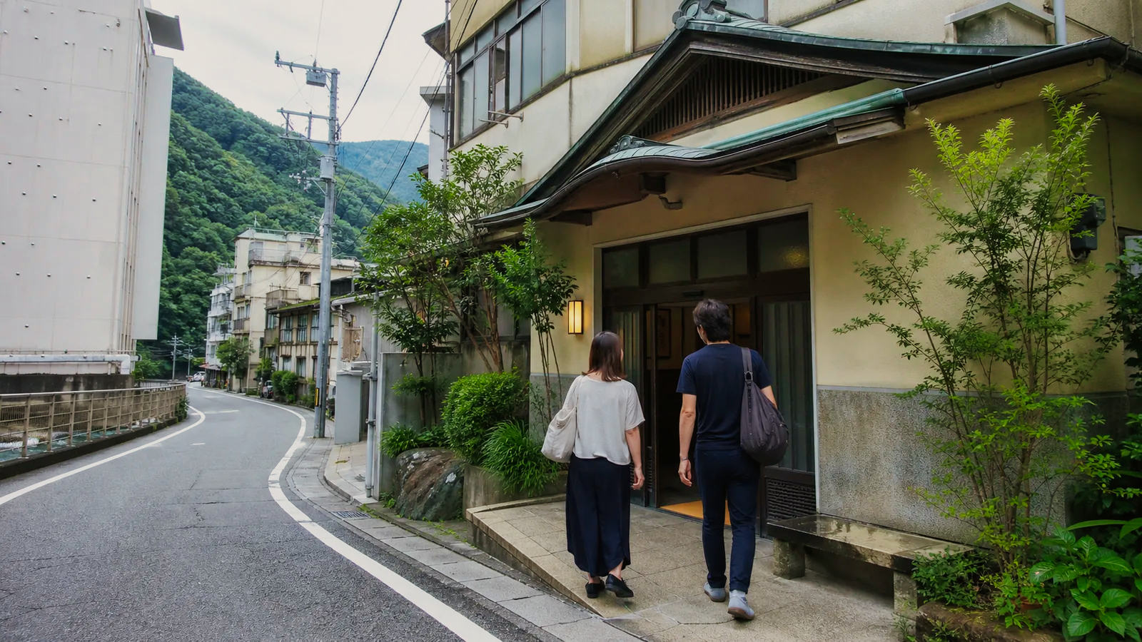 箱根湯本の川沿いにある湯処へ向かう二人の旅行者の編集イメージ