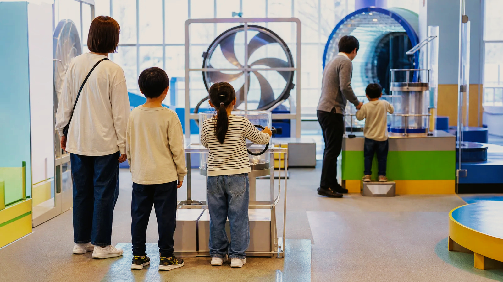 明るい屋内で科学体験装置を試す親子の編集イメージ