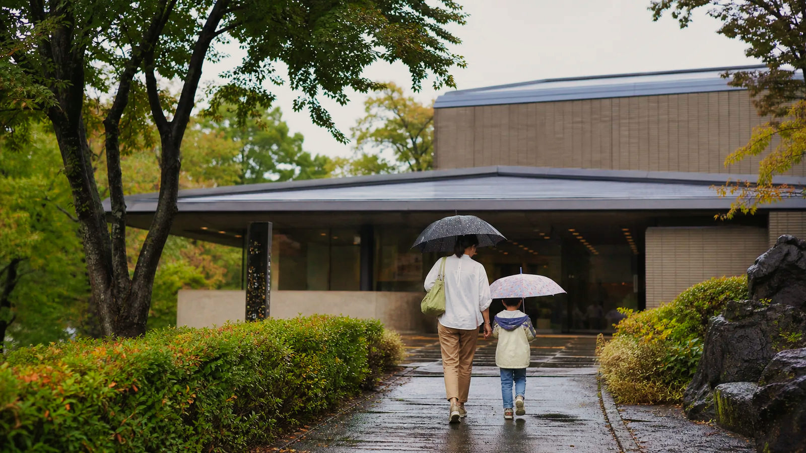 雨の日に盛岡市遺跡の学び館を思わせる文化施設へ入る親子