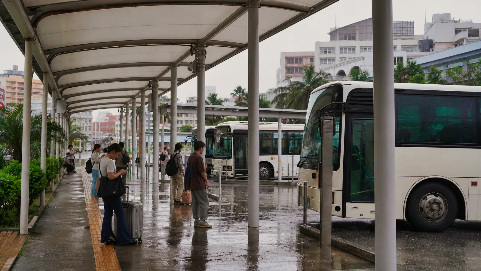 雨の那覇バスターミナルで運行情報を確認する旅行者