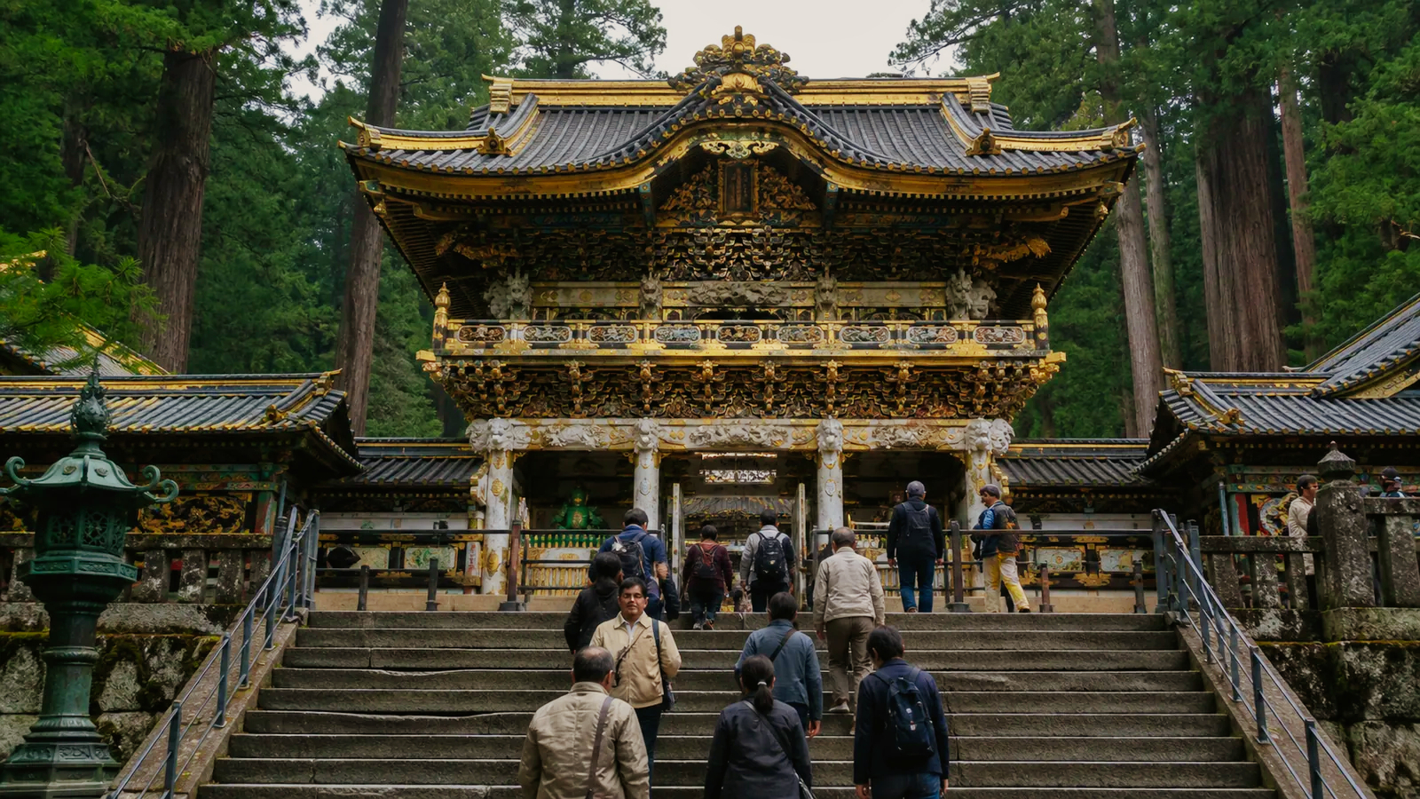 日光東照宮を思わせる色彩豊かな門と杉木立を訪ねる旅行者