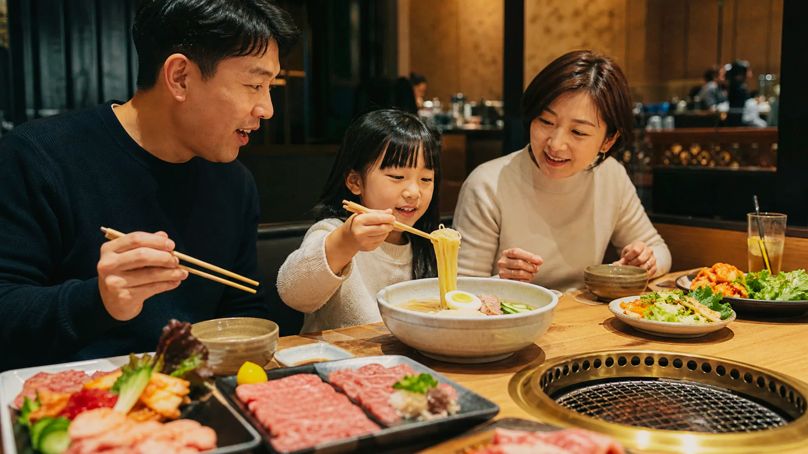 広い焼肉店を思わせるテーブルで家族が盛岡冷麺を囲む様子