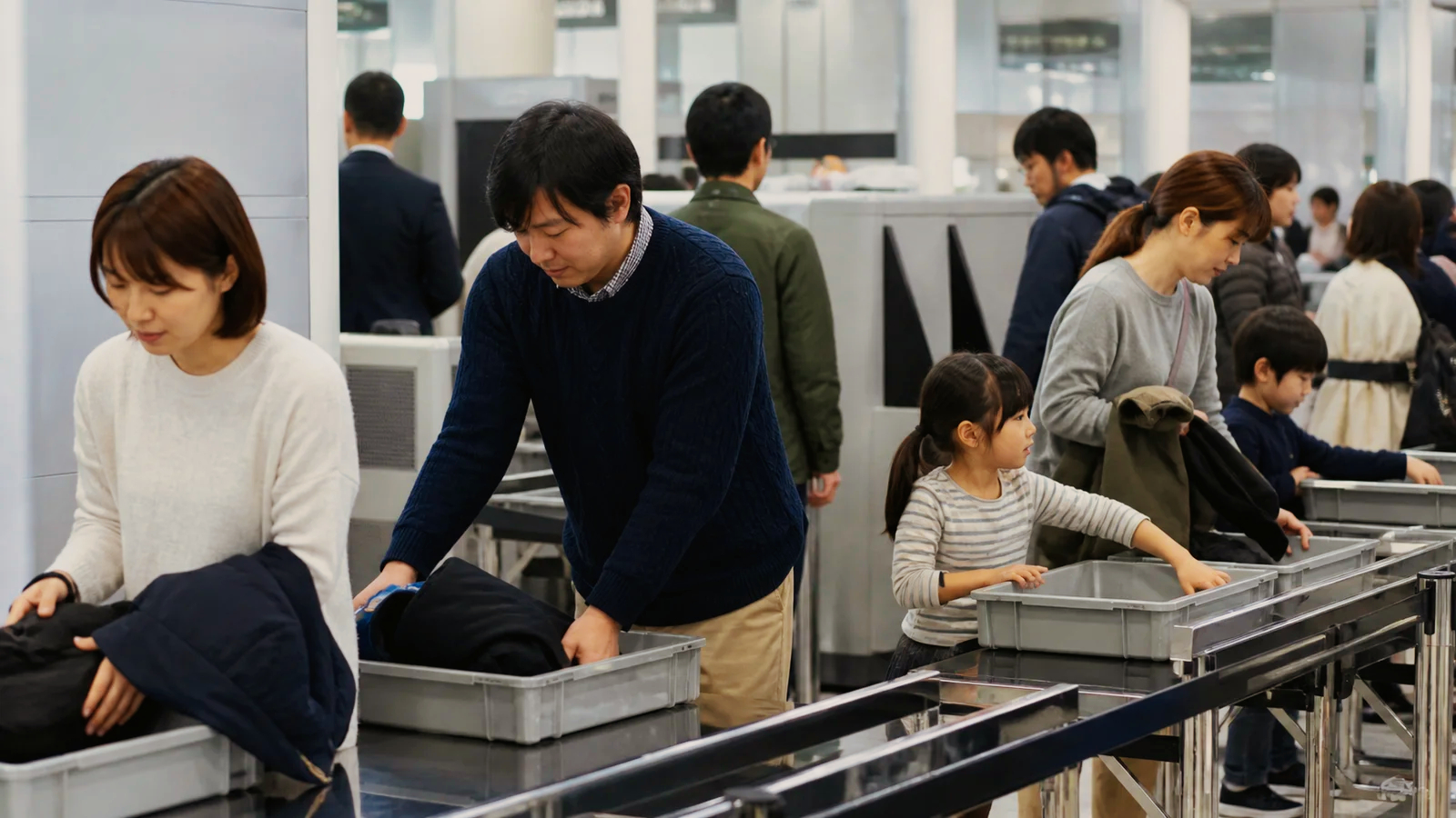 国内線空港の保安検査場でトレーを準備する旅行者
