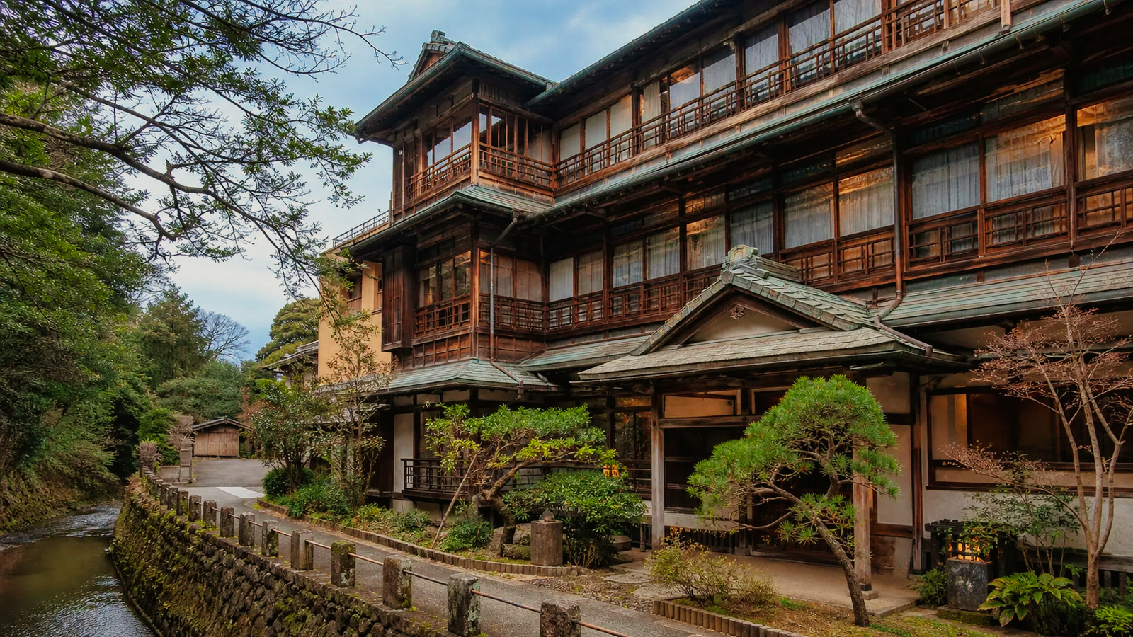 伊東の歴史的な木造旅館建築を川沿いから見た編集イメージ