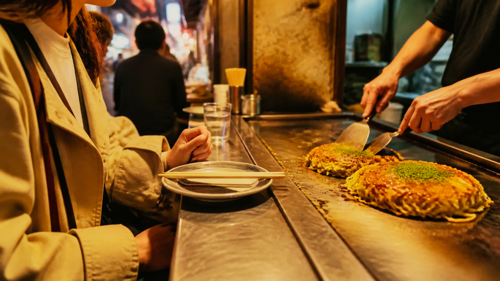 新天地の小さな鉄板カウンターでお好み焼きを味わう場面の編集イメージ