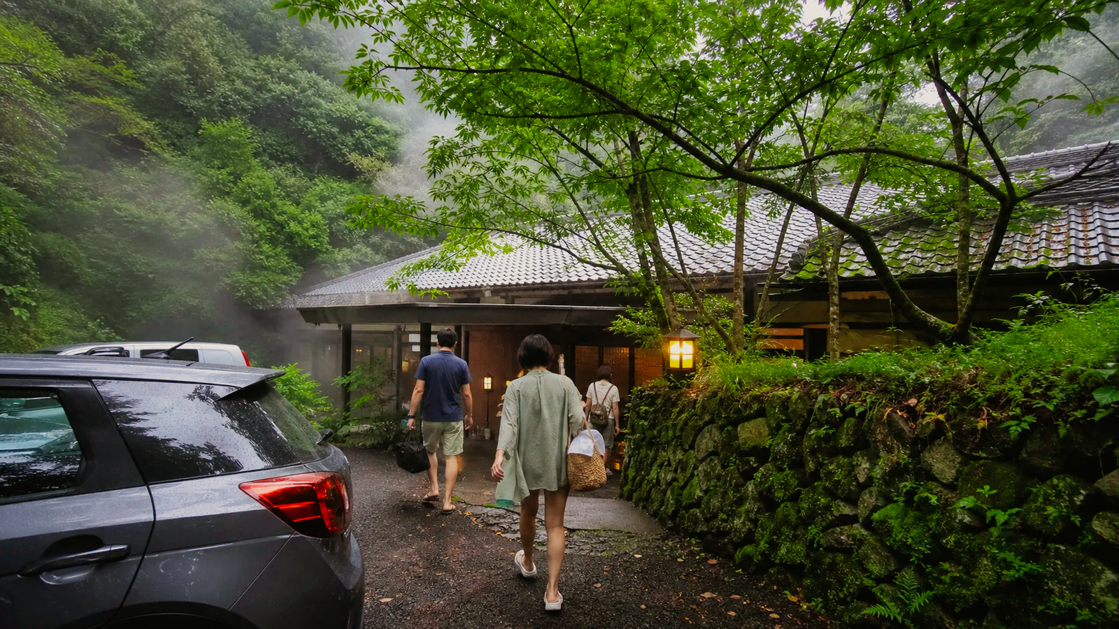 別府郊外の緑に囲まれた温泉施設を思わせる建物へ向かう旅行者