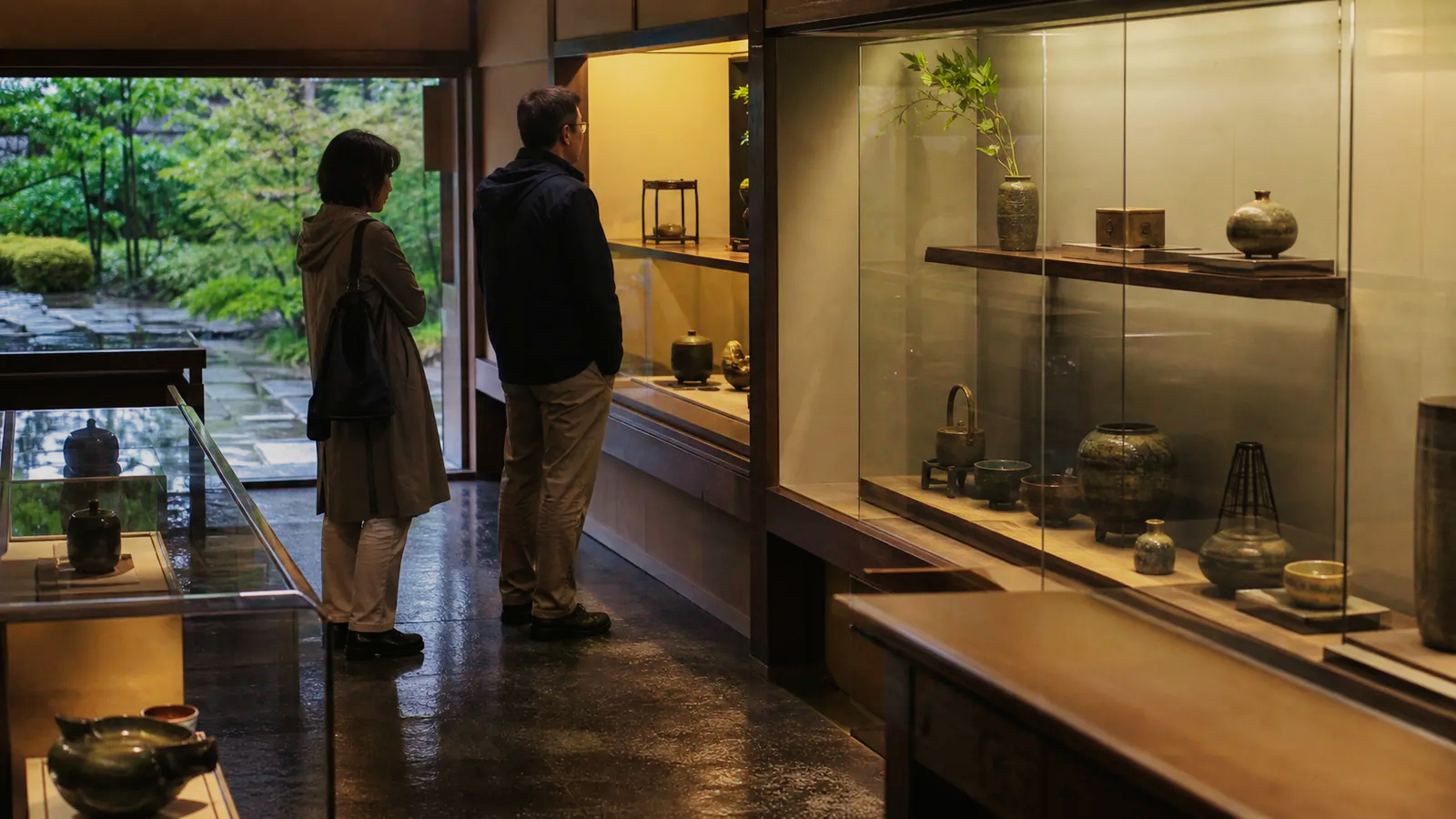 雨の日の小さな美術館で茶道具と工芸品を見る二人の編集イメージ