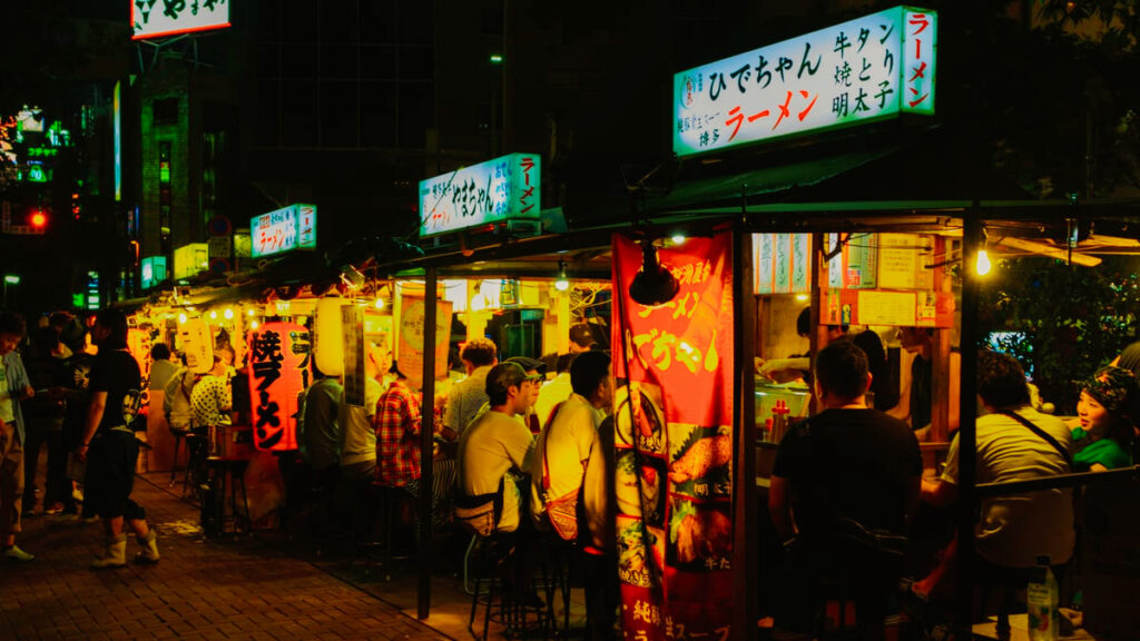 夜の中洲に看板を灯して並ぶ福岡の屋台と利用客