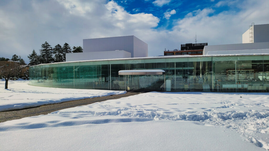 雪に囲まれた金沢21世紀美術館のガラス張り入口（2026年1月）