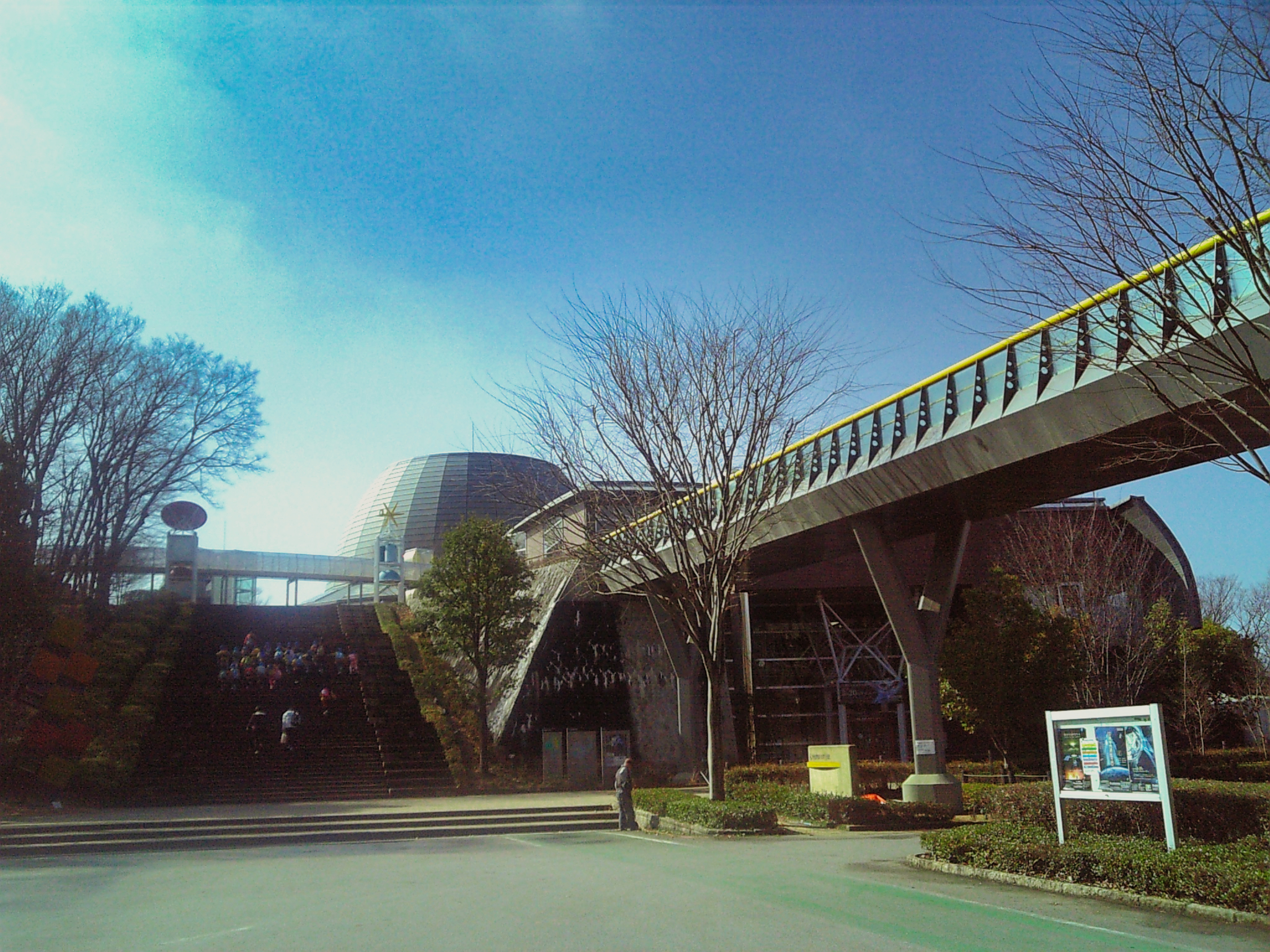 歩道橋とドーム屋根が見える山梨県立科学館の外観