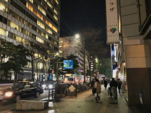 夜の福岡・天神の明治通りを行き交う車と歩行者