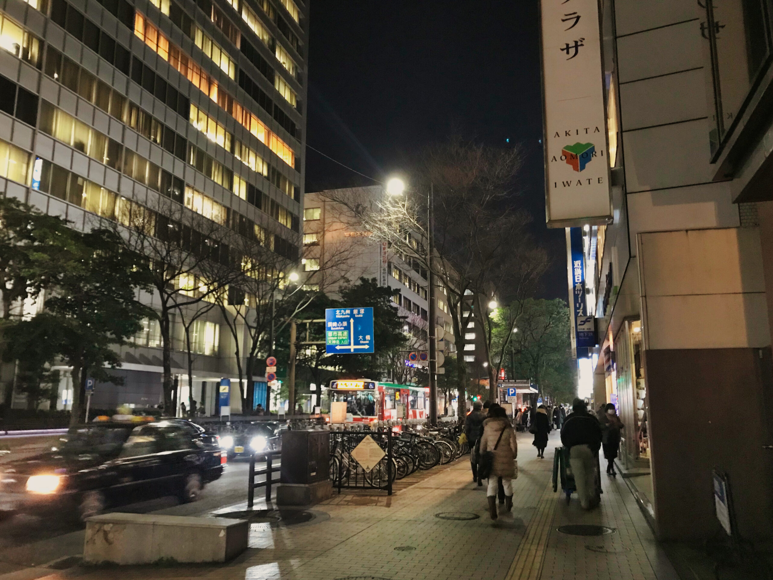 夜の福岡・天神の明治通りを行き交う車と歩行者