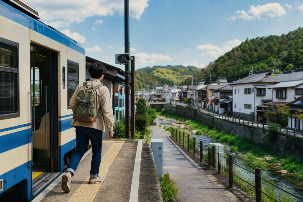 ローカル線を降りて川沿いの町へ向かう旅行者